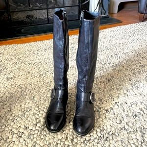 Black knee high leather boots with flat heel, buckle detail.